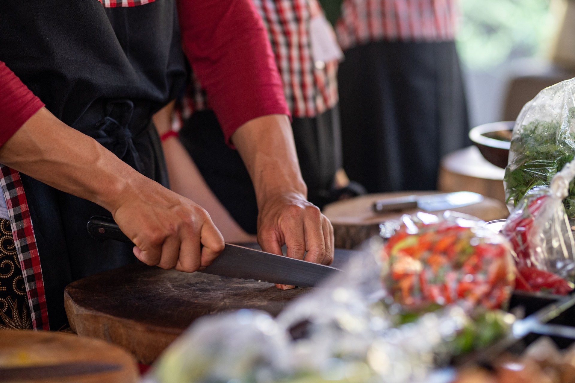 Chef instructing cooking class demonstrates to students how to hold a knife while chopping
